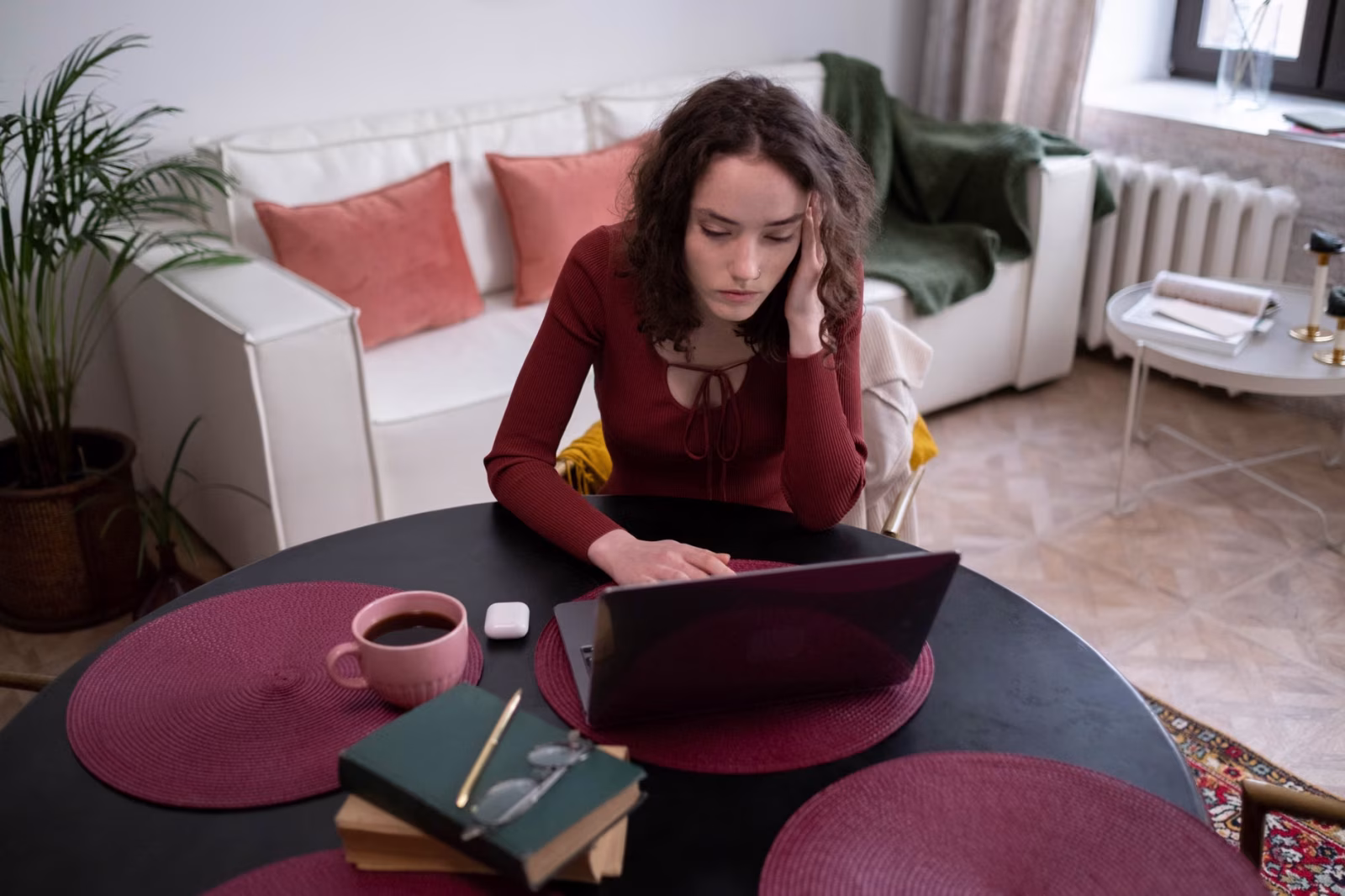 Young woman focused on laptop work with a cup of coffee in a cozy home setting.