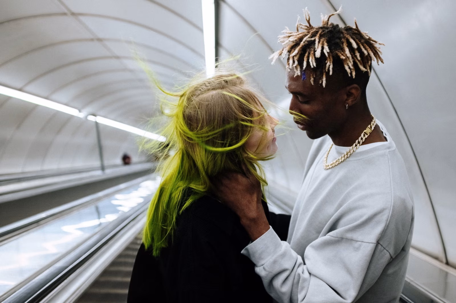 Young couple shares an intimate moment on an underground escalator, capturing urban love.